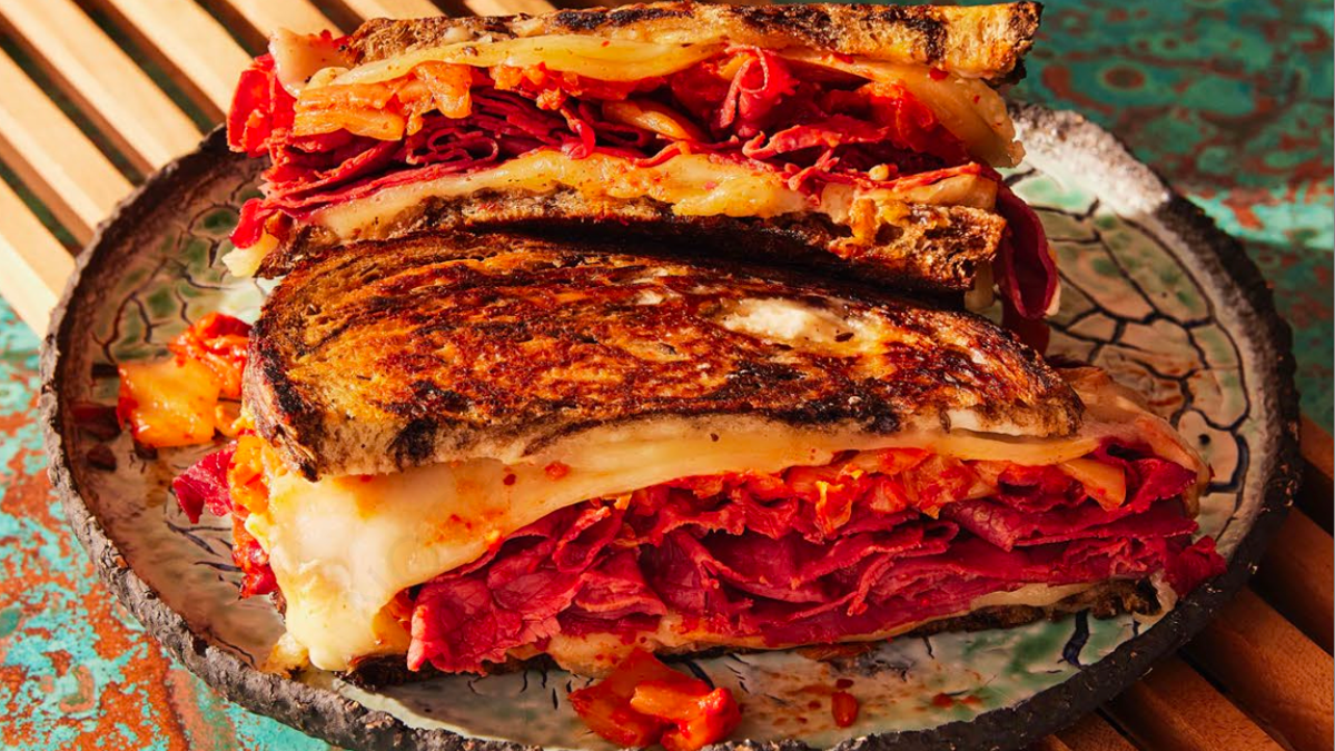 A Reuben sandwich with unconventional ingredients placed on a clay platter.